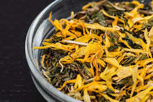 Load image into Gallery viewer, Close up of organic Radiant Glow loose leaf tea with golden calendula petals and other herbs.